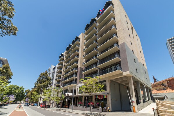 A multi-story hotel with balconies, a ground-level restaurant, and a clear blue sky. - Starwest Apartments Alderney on Hay (East Perth)