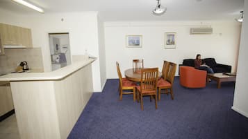 A compact living space with a kitchen area, a dining table with chairs, a sofa, and a coffee table.