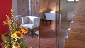 Un interior moderno con un separador de vidrio, un área de comedor con sillas y una escalera.