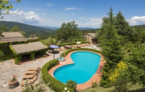 A swimming pool with sun loungers and a stone patio. - Hotel Rifugio Prategiano (Montieri)