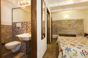 A bathroom with a toilet, sink, and mirror, and a bedroom with a bed and nightstand. - Hotel Rifugio Prategiano (Montieri)