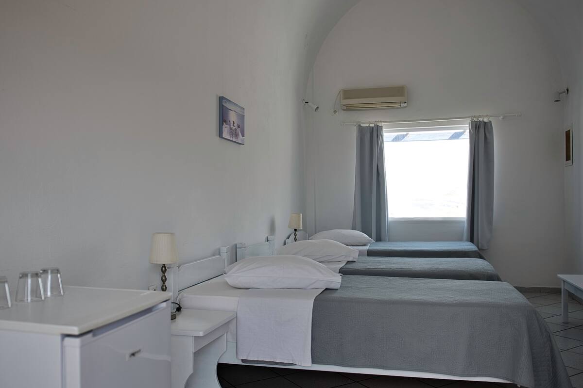 A hotel room with two beds, a desk, and a window with curtains.
