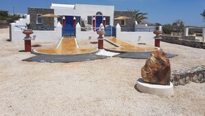 A coastal building with a blue gate, white walls, and a stone pathway leading to the entrance. - Caldera View Resort - Adults Only (Santorini)