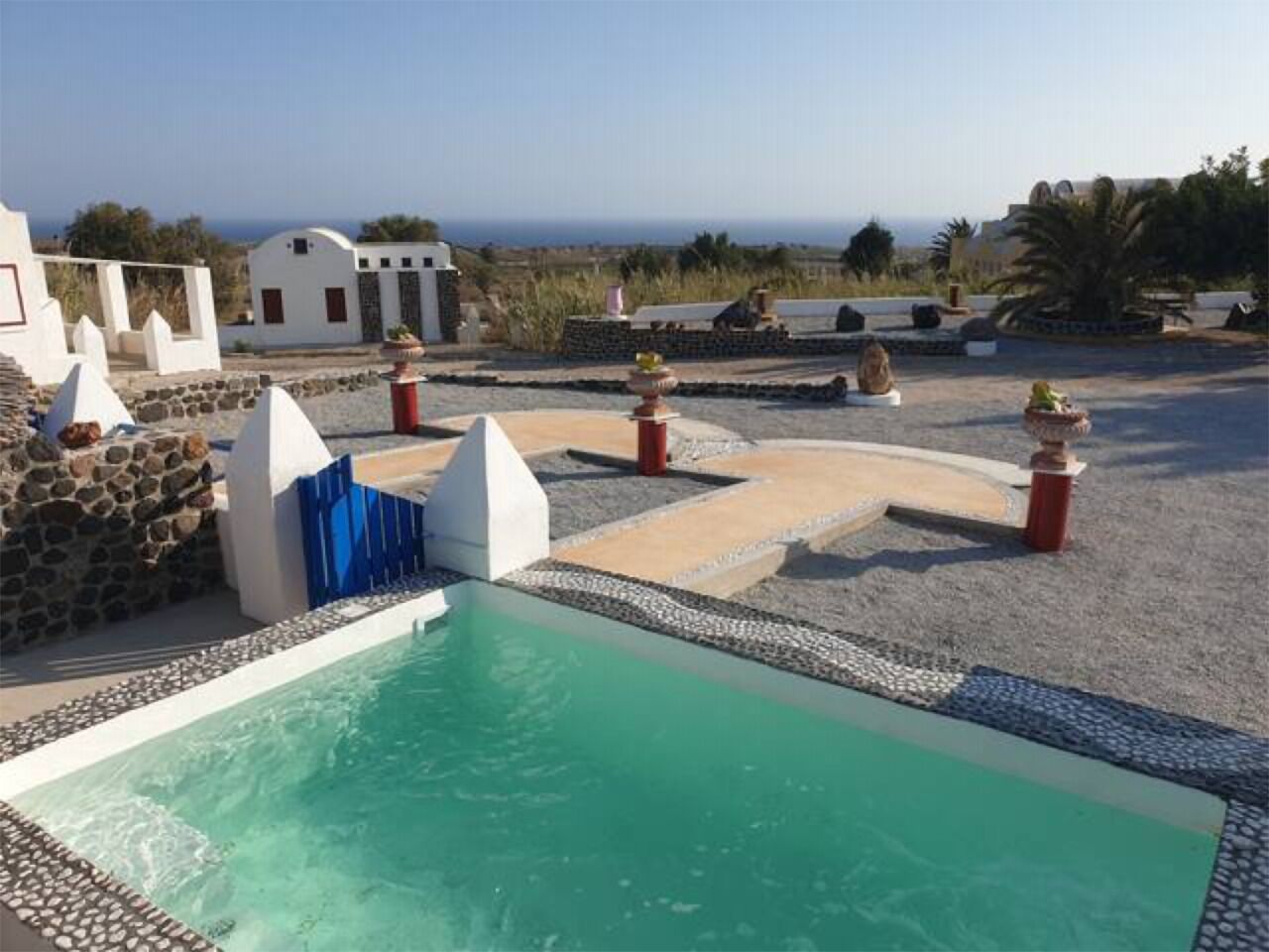 A rooftop pool with a clear view of the ocean, surrounded by white buildings and stone walls.