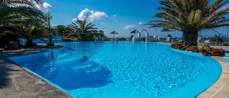 Una piscina al aire libre, sombrillas, tumbonas