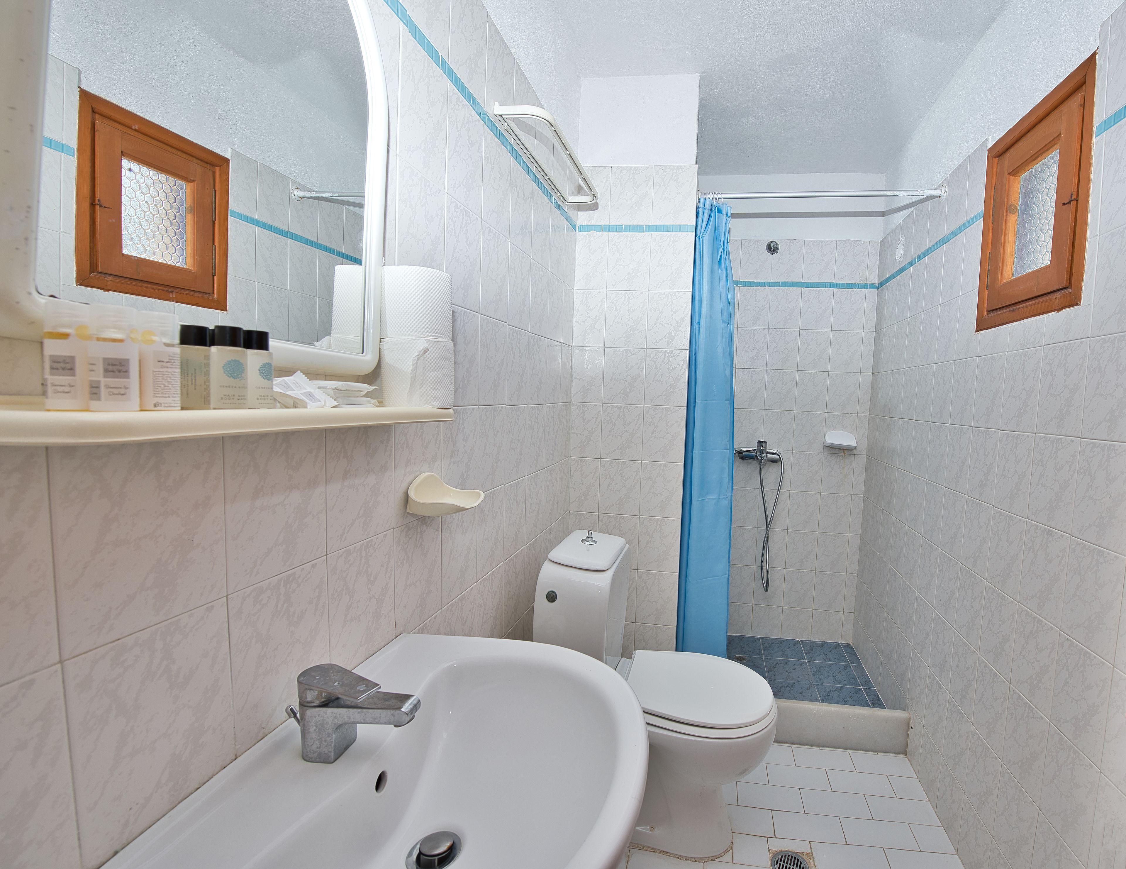 A bathroom with a white sink, toilet, and shower area.