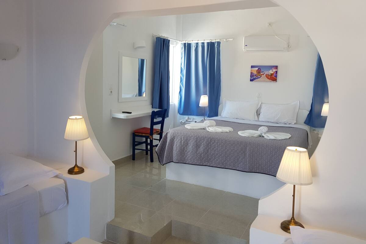 A hotel room with a bed, a desk, a chair, and a bathroom.
