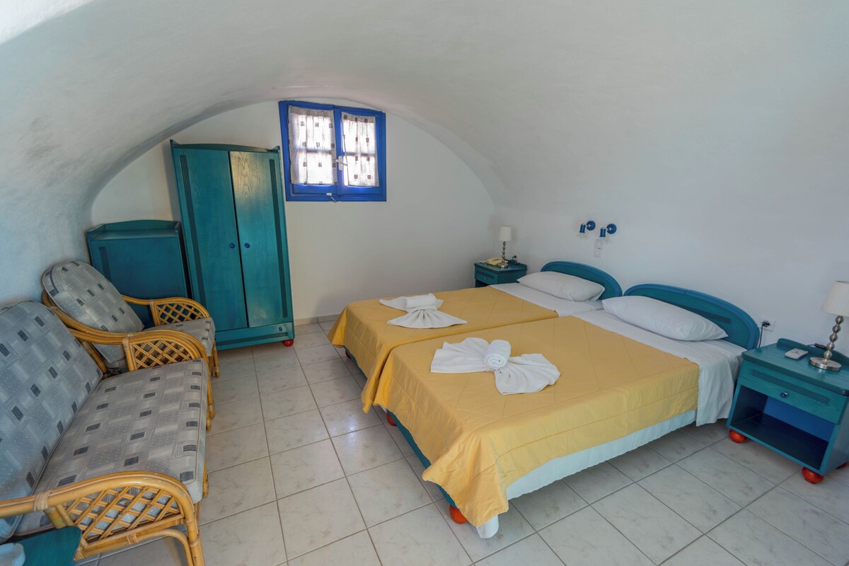 A room with a bed, a sofa, a wardrobe, a nightstand, and a window.