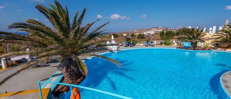 A clear blue pool with a palm tree, a lifebuoy, and a view of the landscape.
