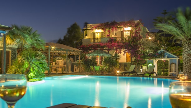 Une piscine avec des chaises longues et une table en verre sur laquelle sont disposées des boissons et des fruits.