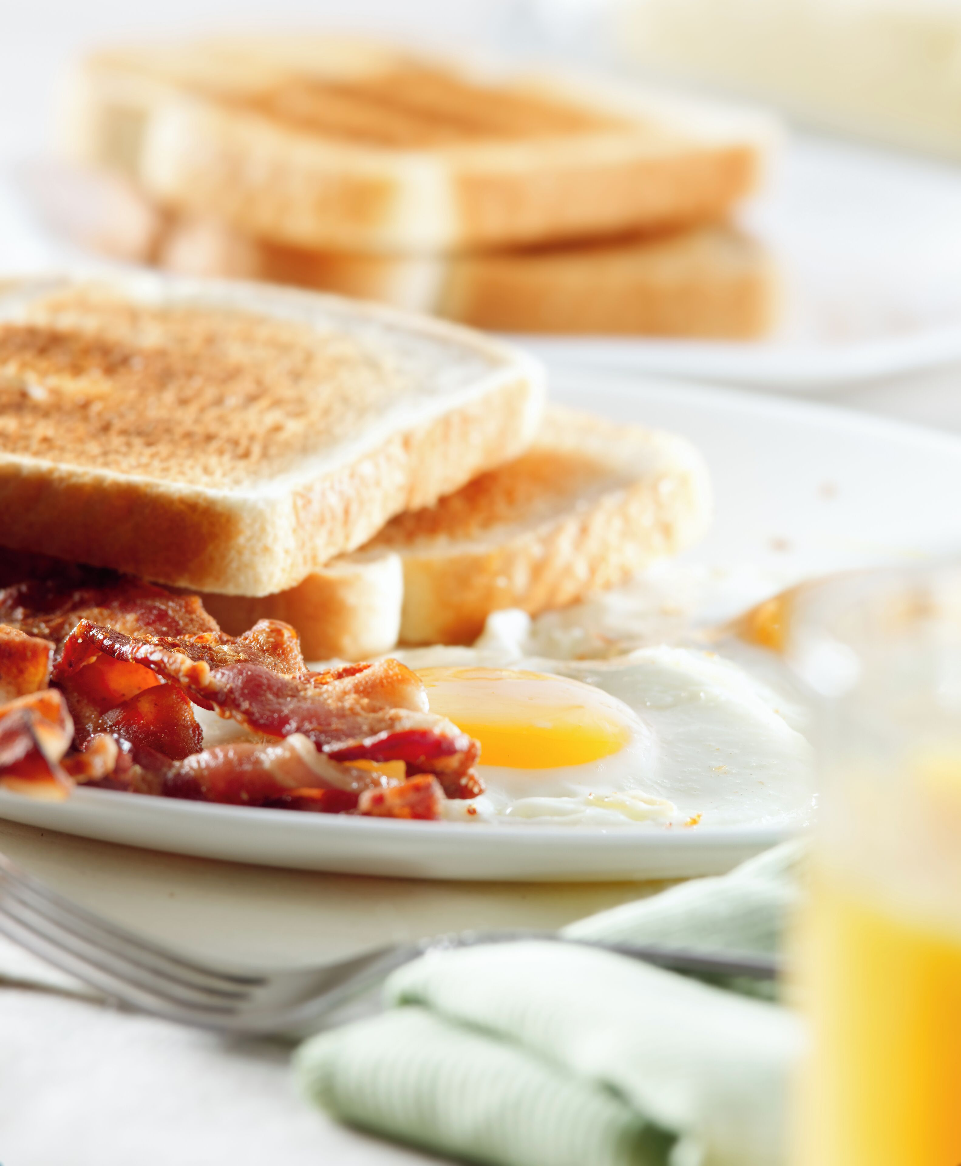 A breakfast plate with toast, bacon, and a fried egg.