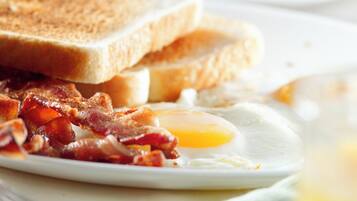 A breakfast plate with toast, bacon, and a fried egg.