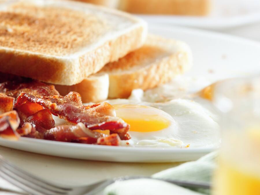 A breakfast plate with toast, bacon, and a fried egg.