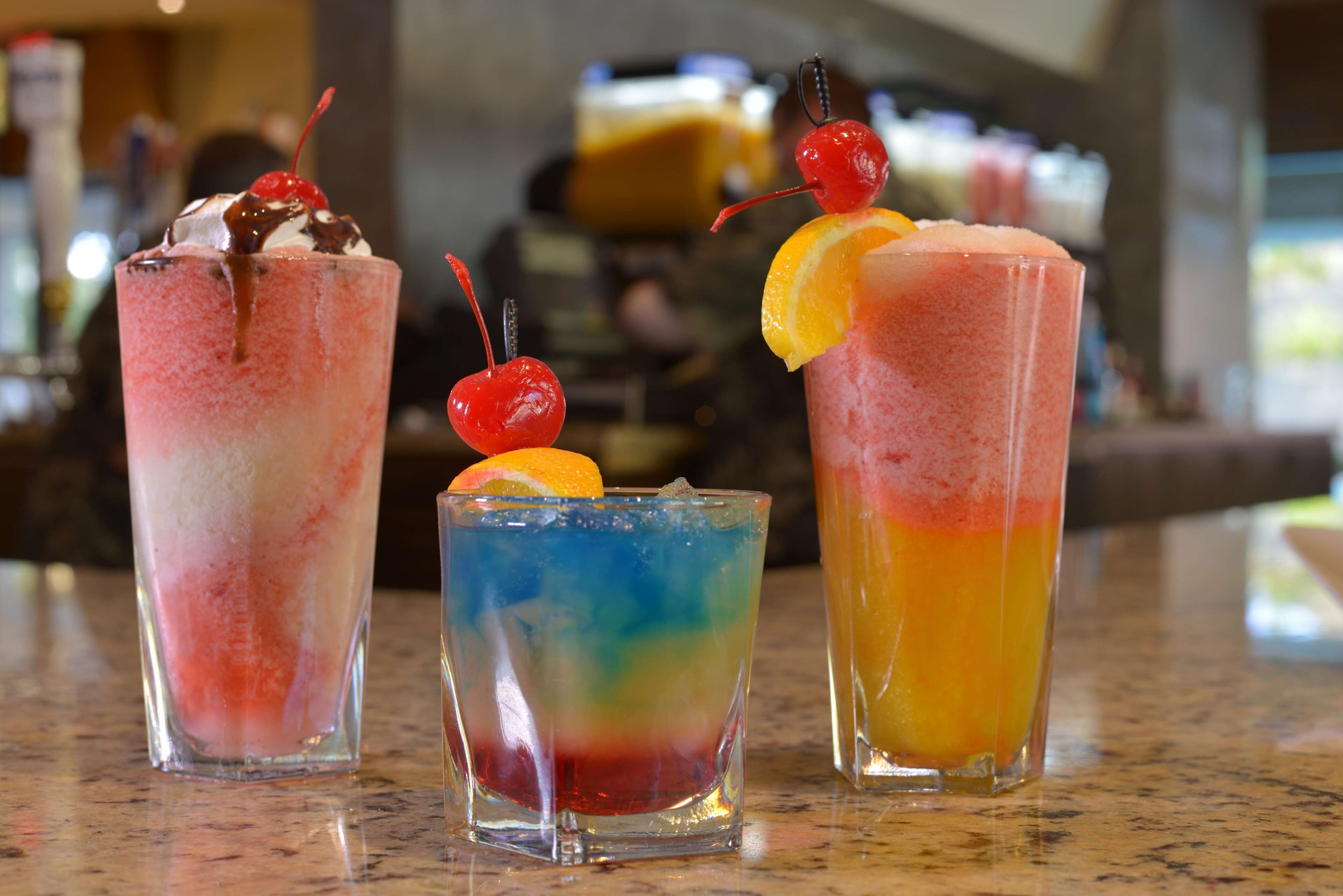 Tres bebidas coloridas sobre una barra.