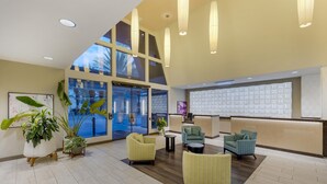 A spacious lobby with modern furniture, large windows, and a reception desk.