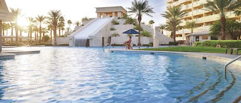 Una piscina al aire libre, sombrillas, sillones reclinables de piscina