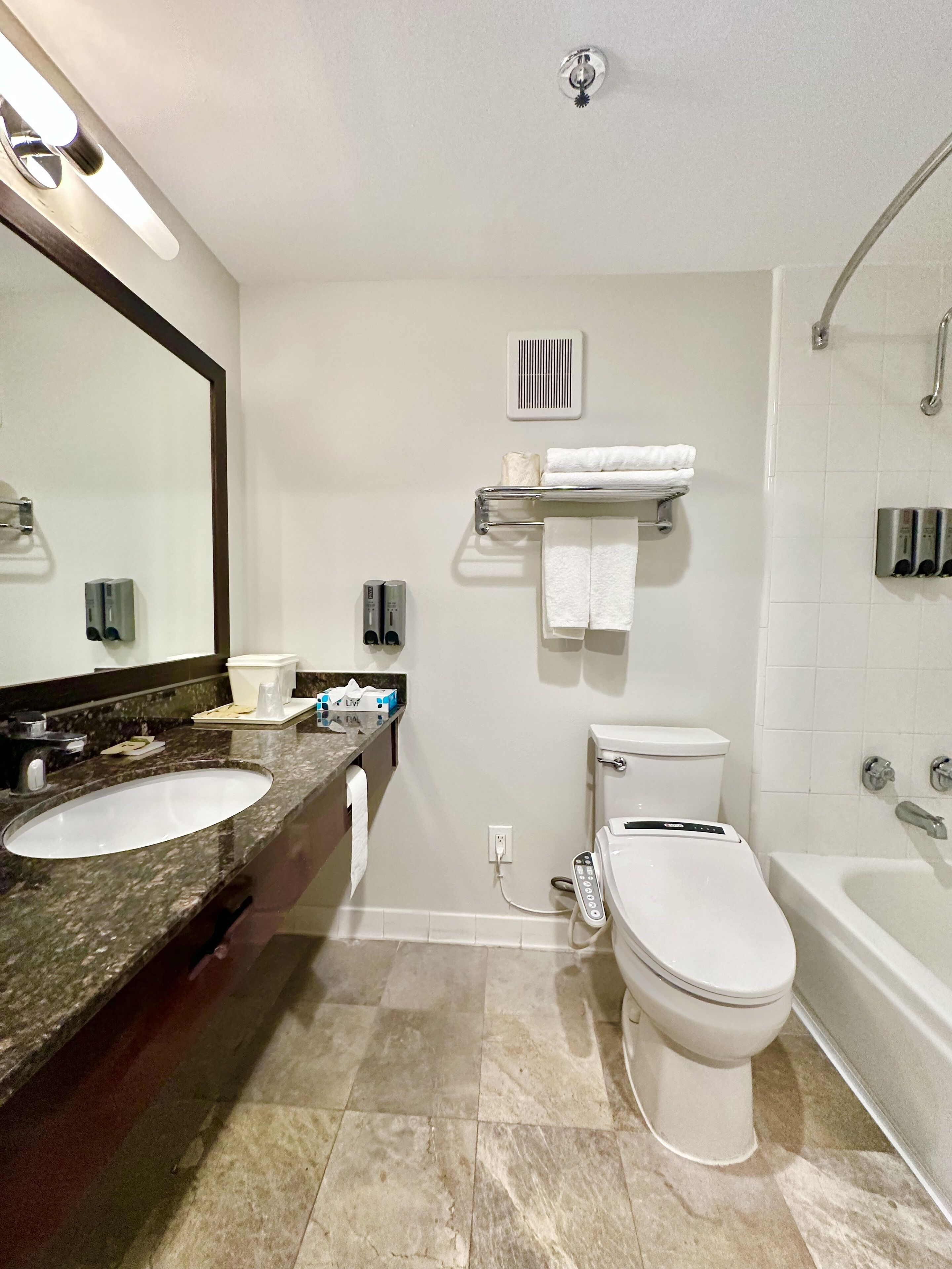 A modern bathroom with two sinks, a toilet, a bathtub, and a shower.