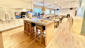 Une cuisine moderne dotée d’un îlot central, de tabourets de bar et d’un long comptoir.