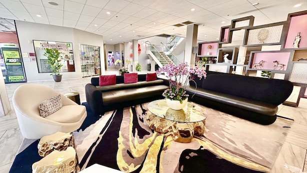 Un intérieur moderne avec un canapé noir, un fauteuil beige et une table basse en verre.