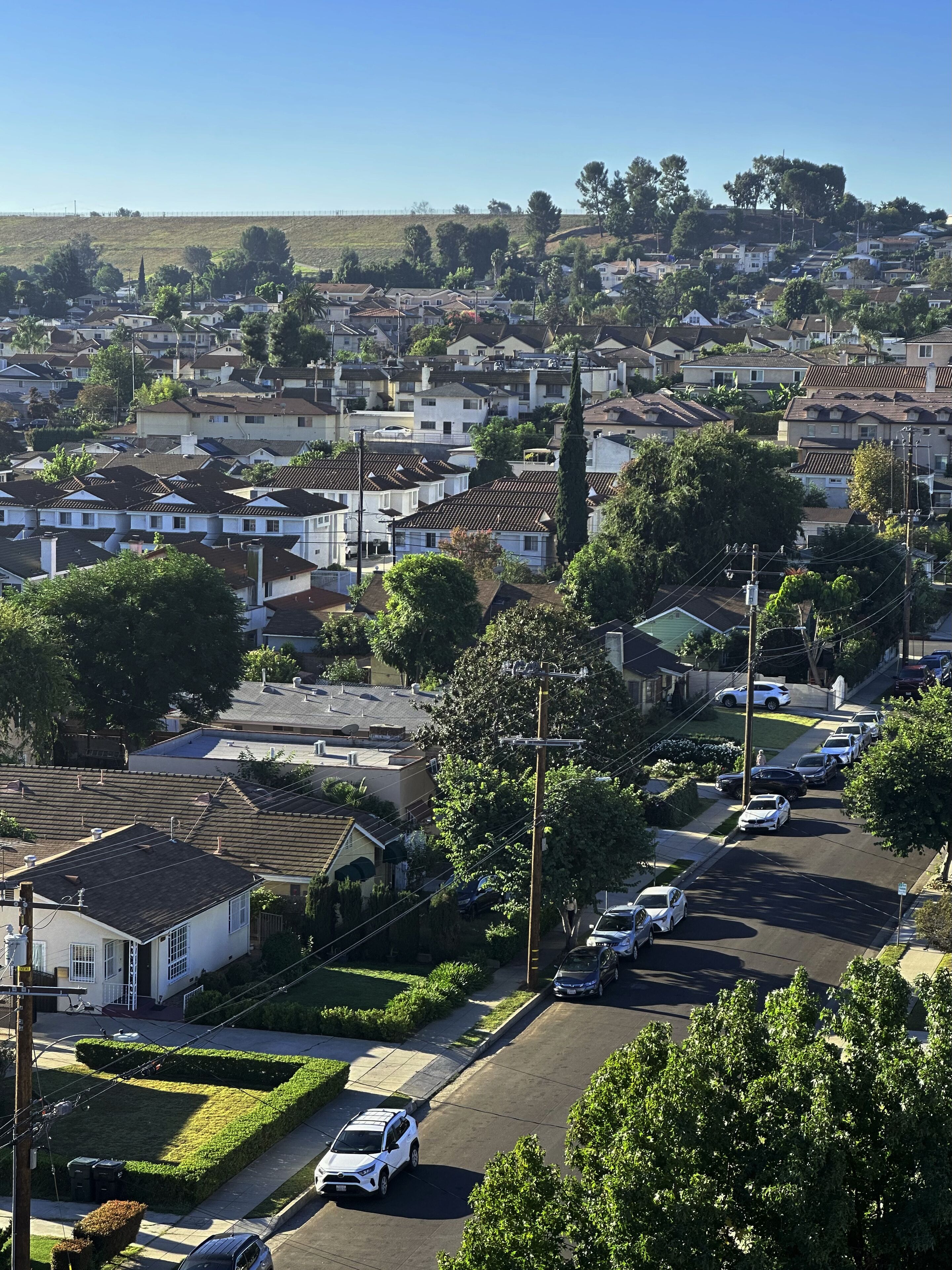 Zona residencial con casas, una calle y coches aparcados.