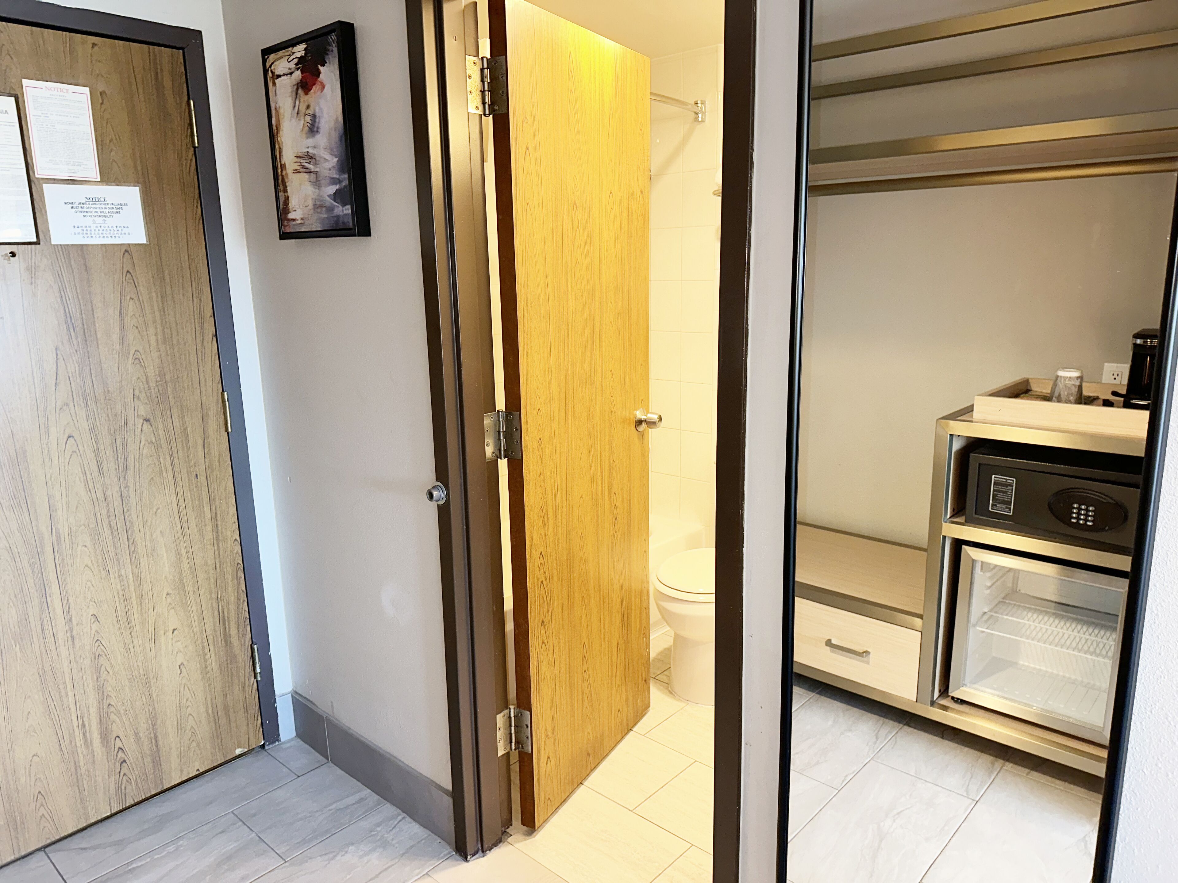 A hotel room with a wooden door, a toilet, and a minibar.