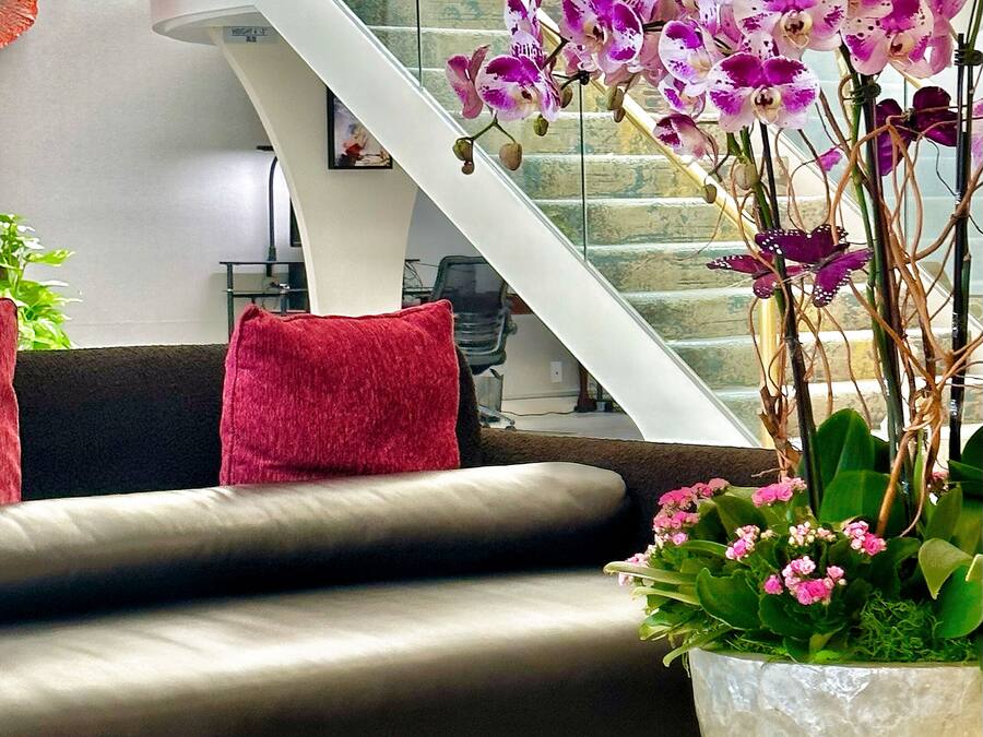 A modern living room with a glass coffee table, a sofa, and a staircase with glass railings.