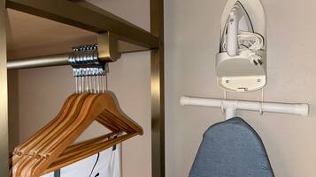 Un perchero de madera y una camisa blanca colgados en una barra metálica en una habitación con pared y techo blancos.