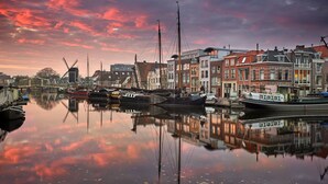 Un canal bordé de bateaux et de bâtiments traditionnels dont l’image se reflète dans l’eau.