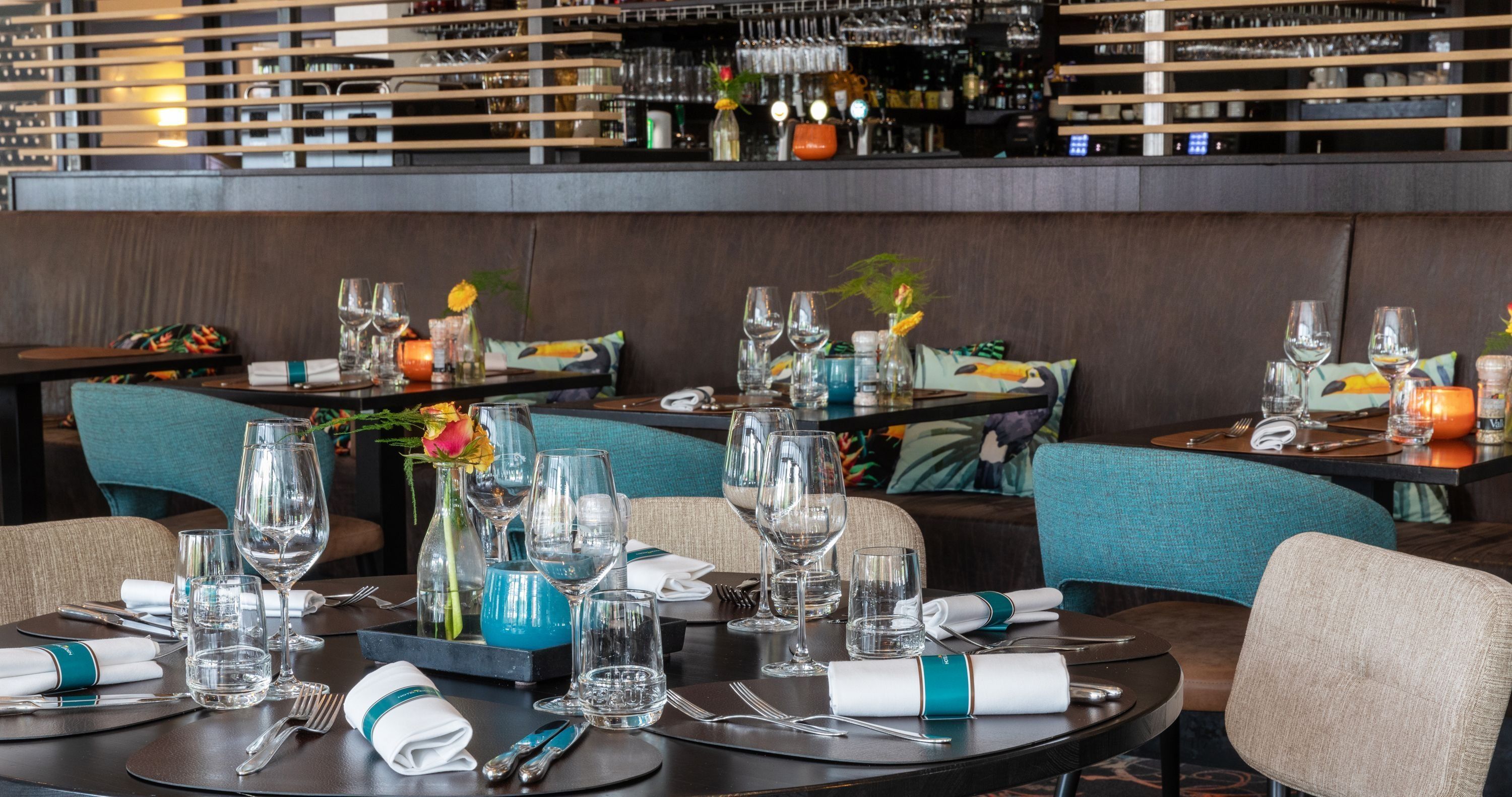 Un restaurante con mesas redondas dispuestas para comer, con vasos transparentes y servilletas.