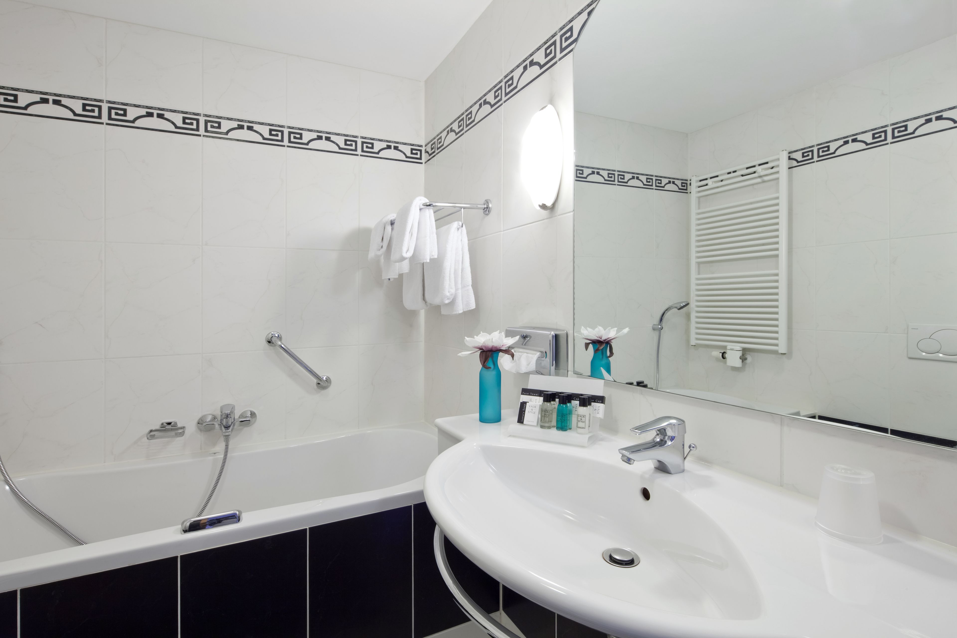 A modern bathroom with a bathtub, a white sink, and a mirror.