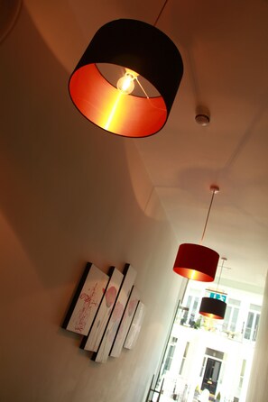 A hallway with modern pendant lights and artwork on the wall. - Exhibition Court Hotel 4 (London)