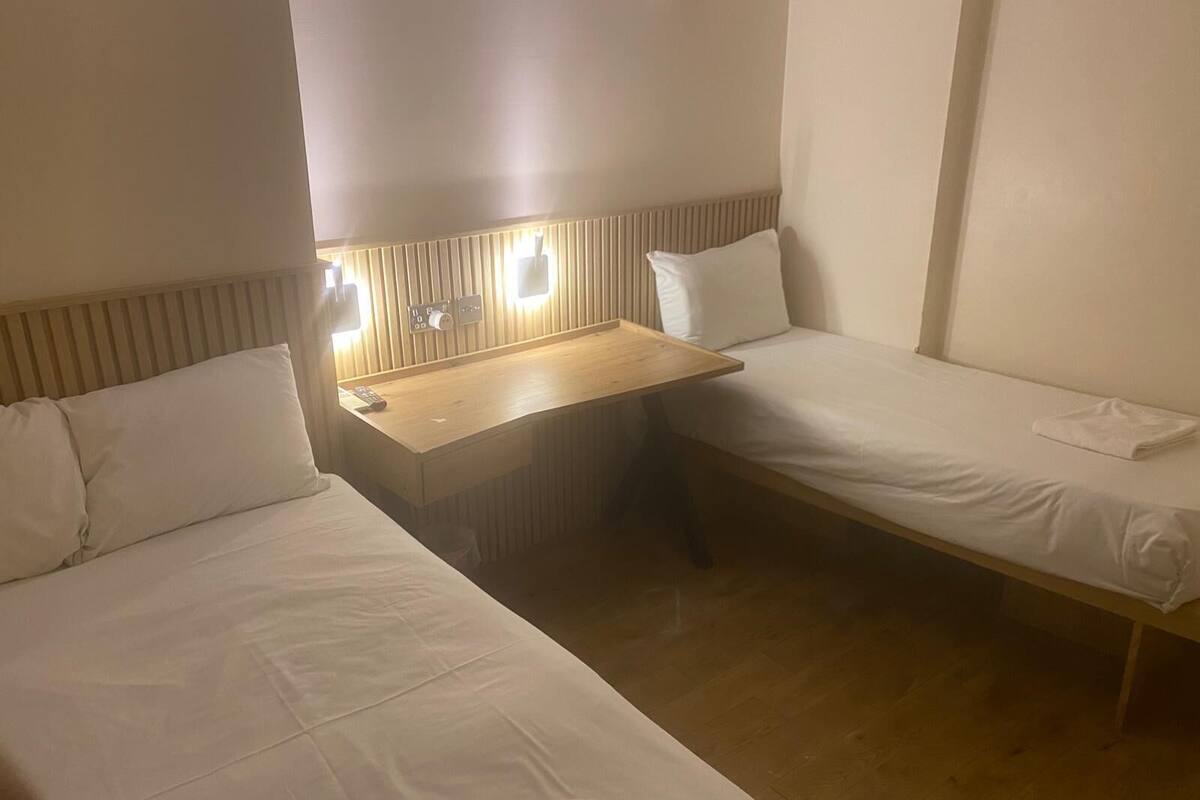 Een hotelkamer met twee enkele bedden, een houten bureau en een wandlamp.