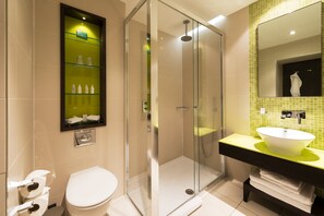 A modern bathroom with a glass-enclosed shower, a white toilet, and a vanity with a green sink. - Hotel Indigo London Hyde Park Paddington by IHG (London)