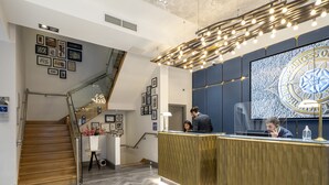 A reception area with a herringbone floor, a staircase, and a large wall-mounted screen displaying a logo.