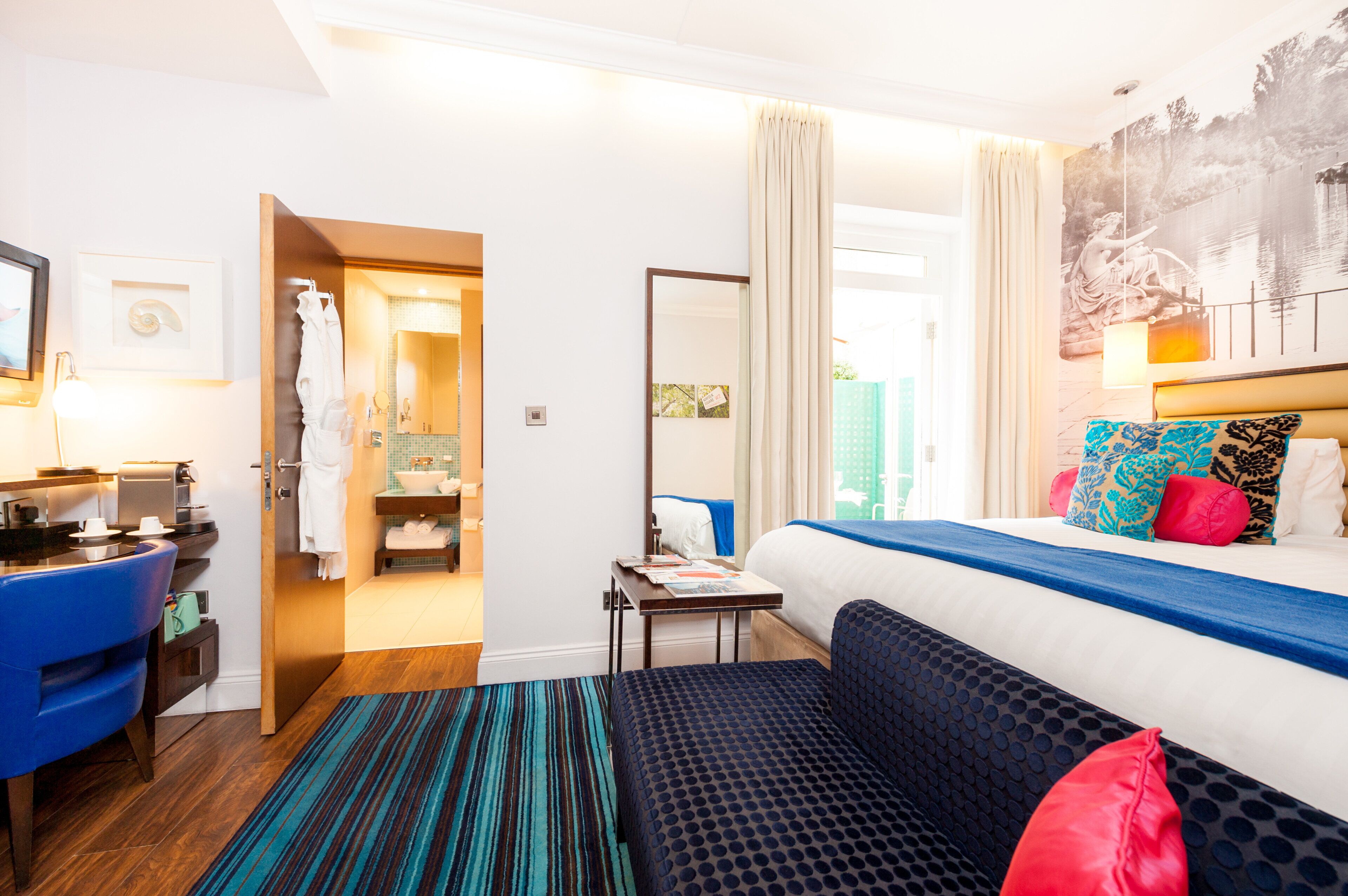 A hotel room with a bed, a desk, a chair, a bathroom, and a view of a lake.