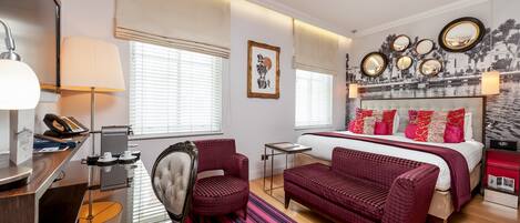 A hotel room with a bed, a desk, a chair, a sofa, and a large mirror.