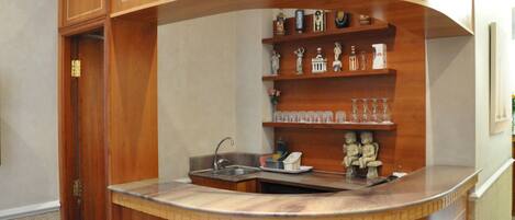 A kitchen with wooden cabinetry, a sink, and shelves with various items.