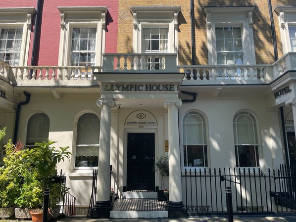 The front of the Olympic House Hotel with a classical facade, large windows, and a prominent entrance. - Olympic House Hotel (London)