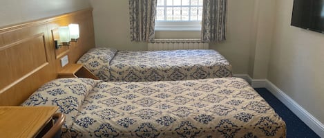 Camera d'albergo con due letti, una testiera in legno, una scrivania, una finestra con tende e un televisore fissato al muro.