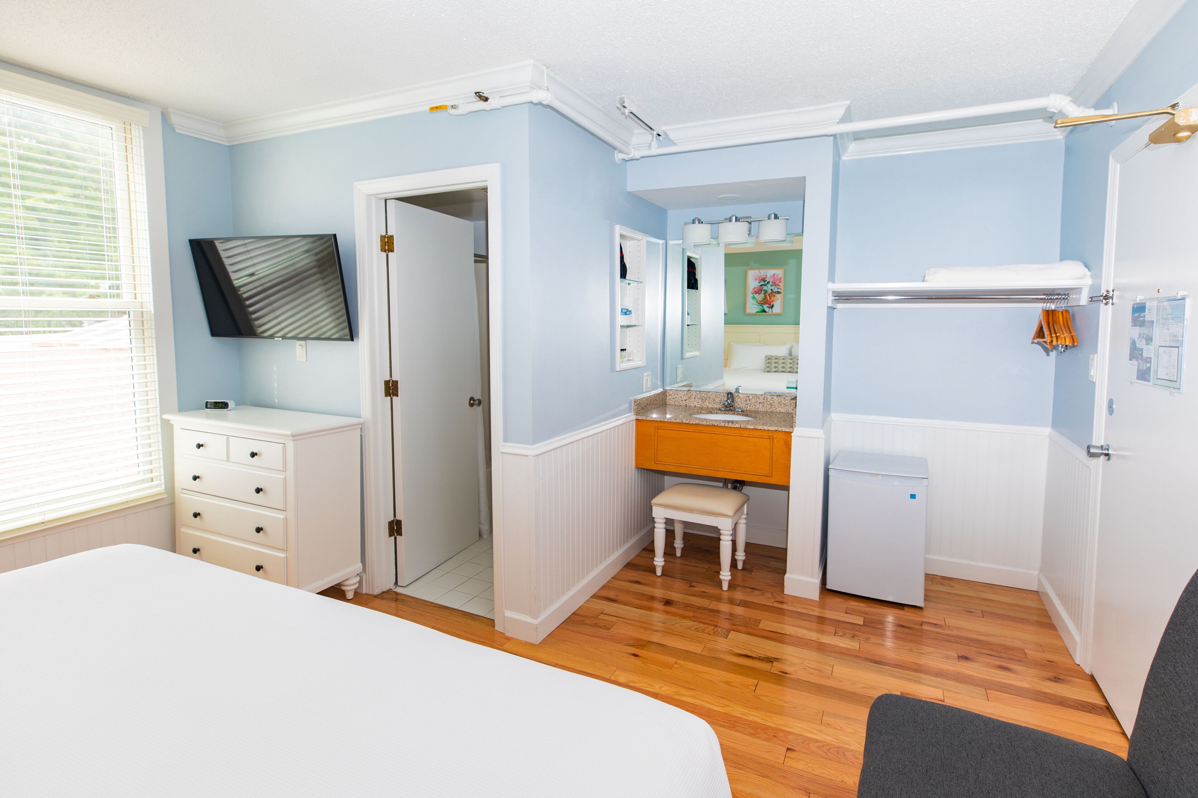Ein Schlafzimmer mit einem Bett, einem Schminktischchen, einem Hocker und einem Heizgerät.