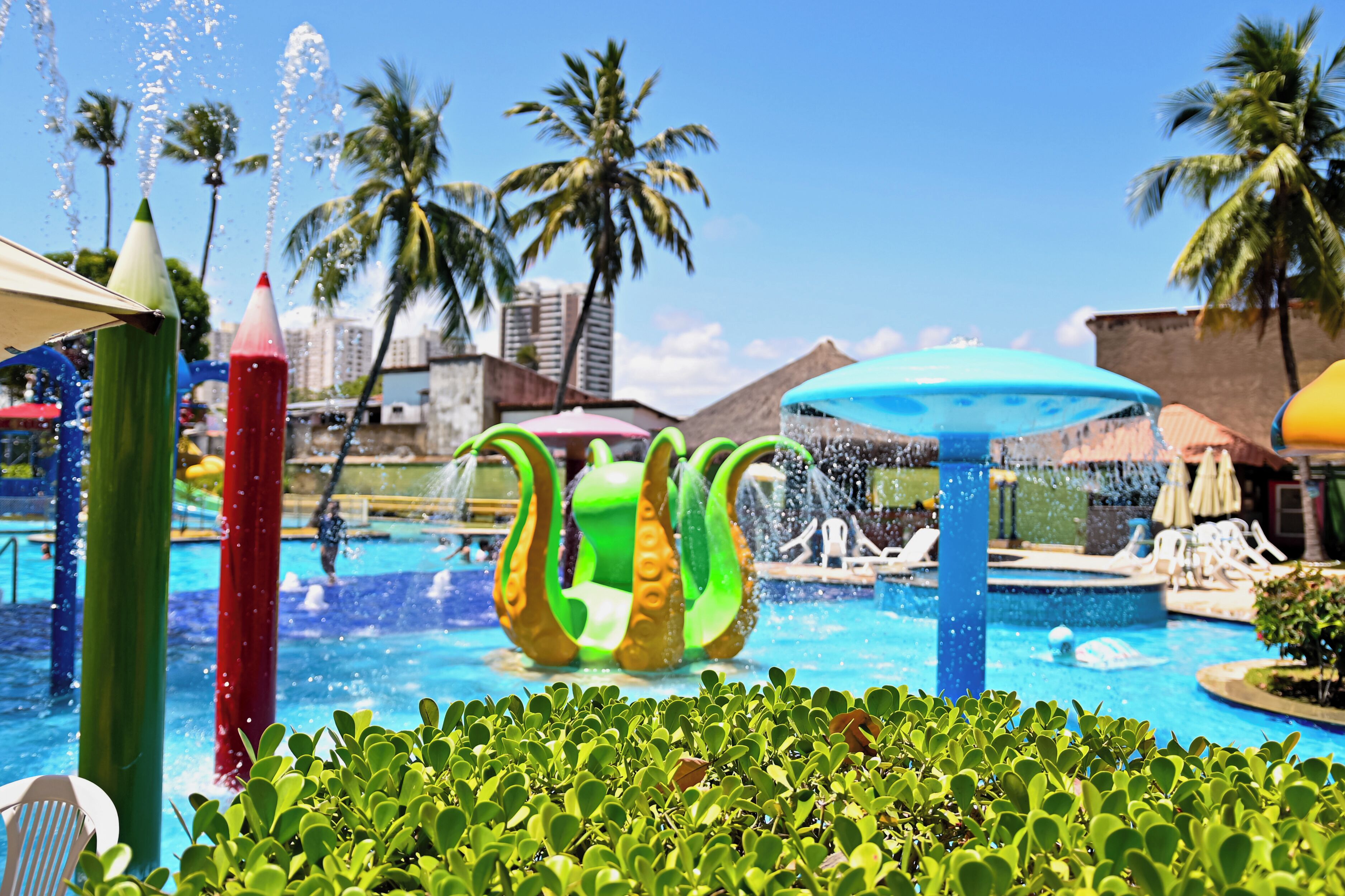 A pool area with water features, palm trees, and lounge chairs.
