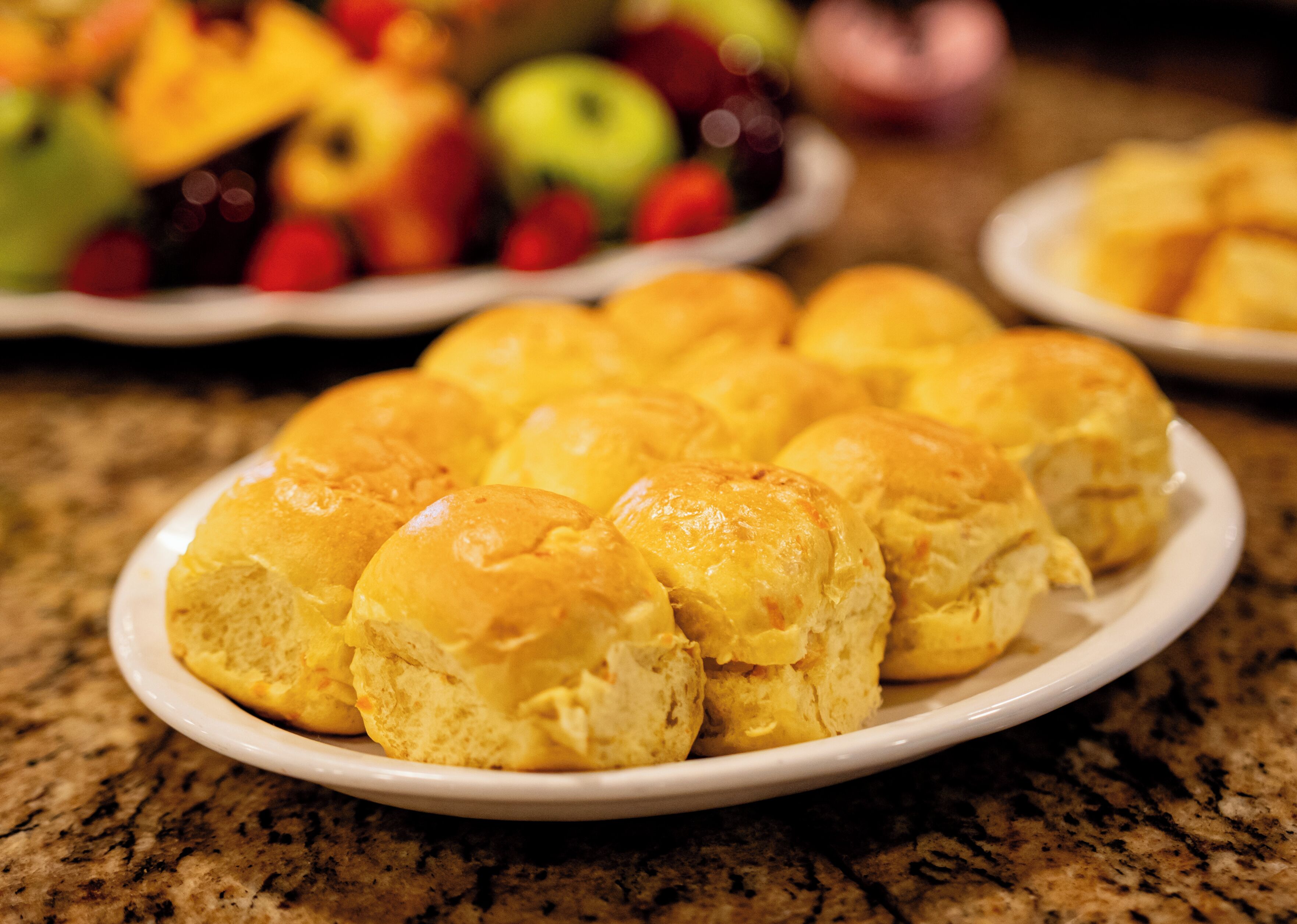 A plate of freshly baked dinner rolls on a granite countertop.