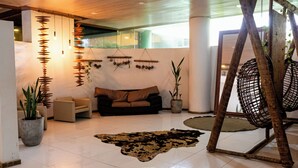A modern living room with a sofa, a hanging light fixture, and a large potted plant. - Matsubara Acqua Park Hotel (Maceió)