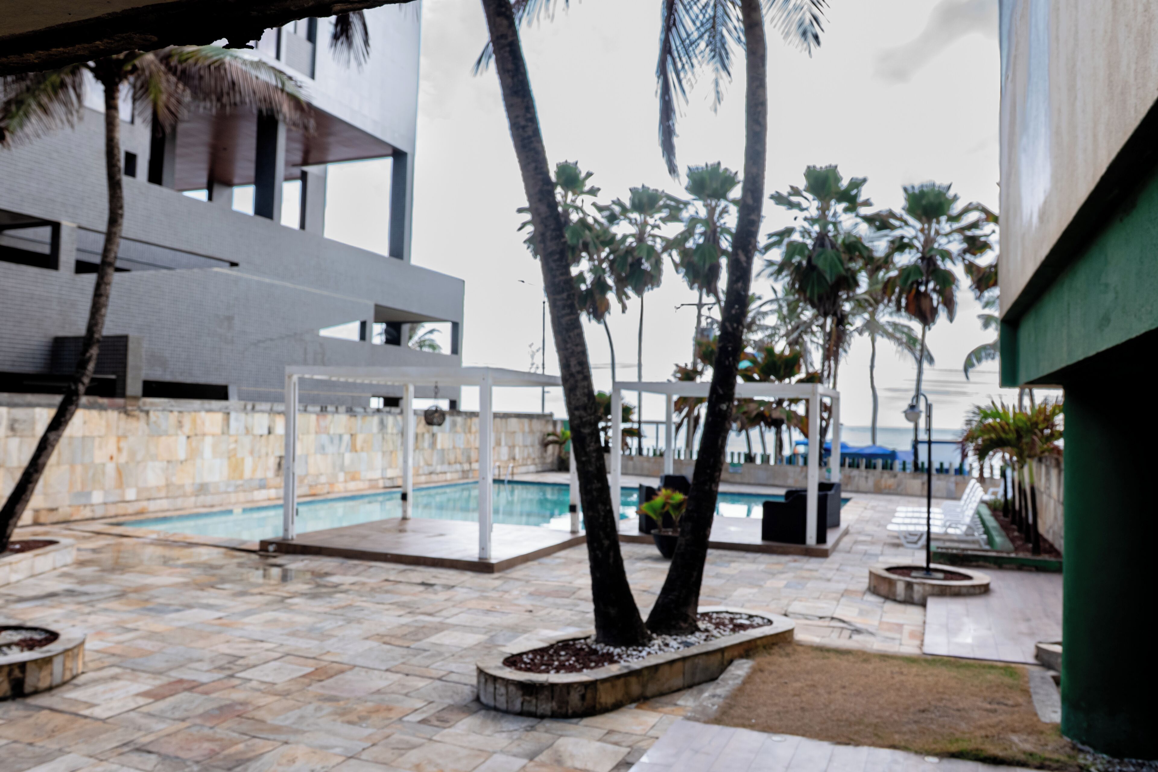 A pool area with palm trees, a modern building, and a clear sky.