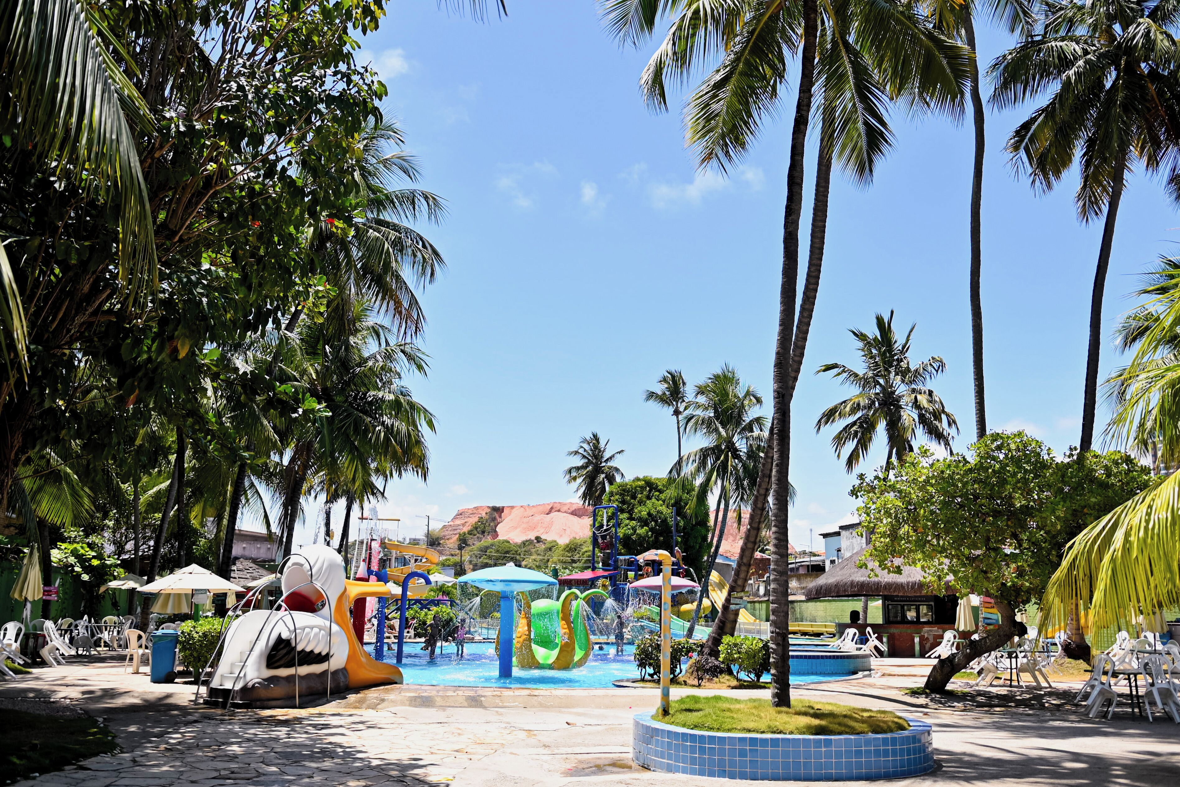 A water park with slides and a pool area, surrounded by palm trees and lounge chairs.