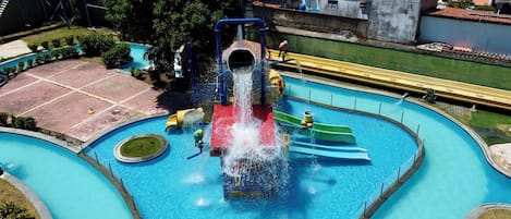Een waterpark met een centrale glijbaan, meerdere zwembaden en veel groen eromheen.