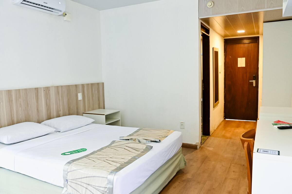 Una habitación de hotel con una cama, una mesita de noche y un escritorio con una silla.
