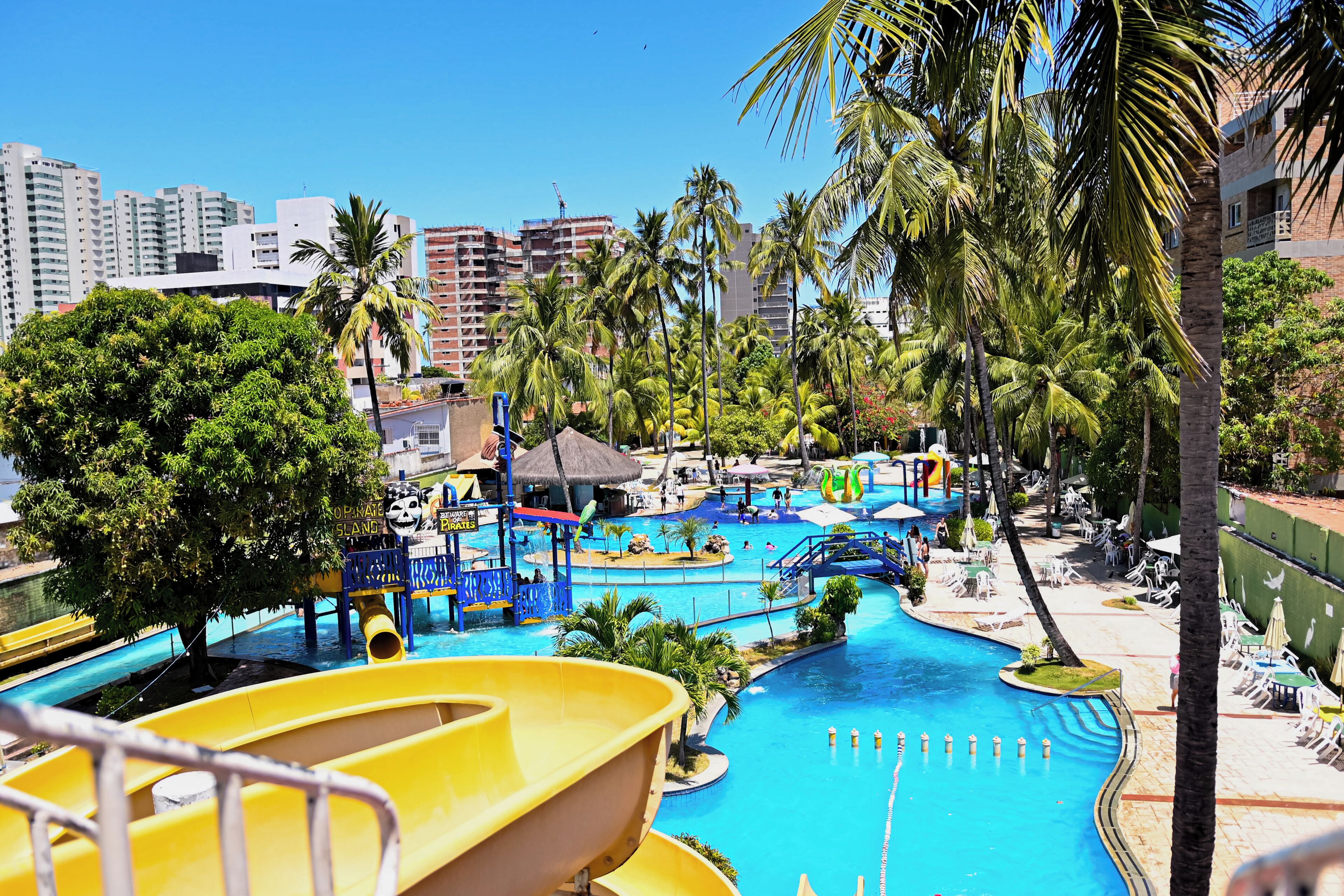 A water park with slides and pools, surrounded by palm trees and buildings.
