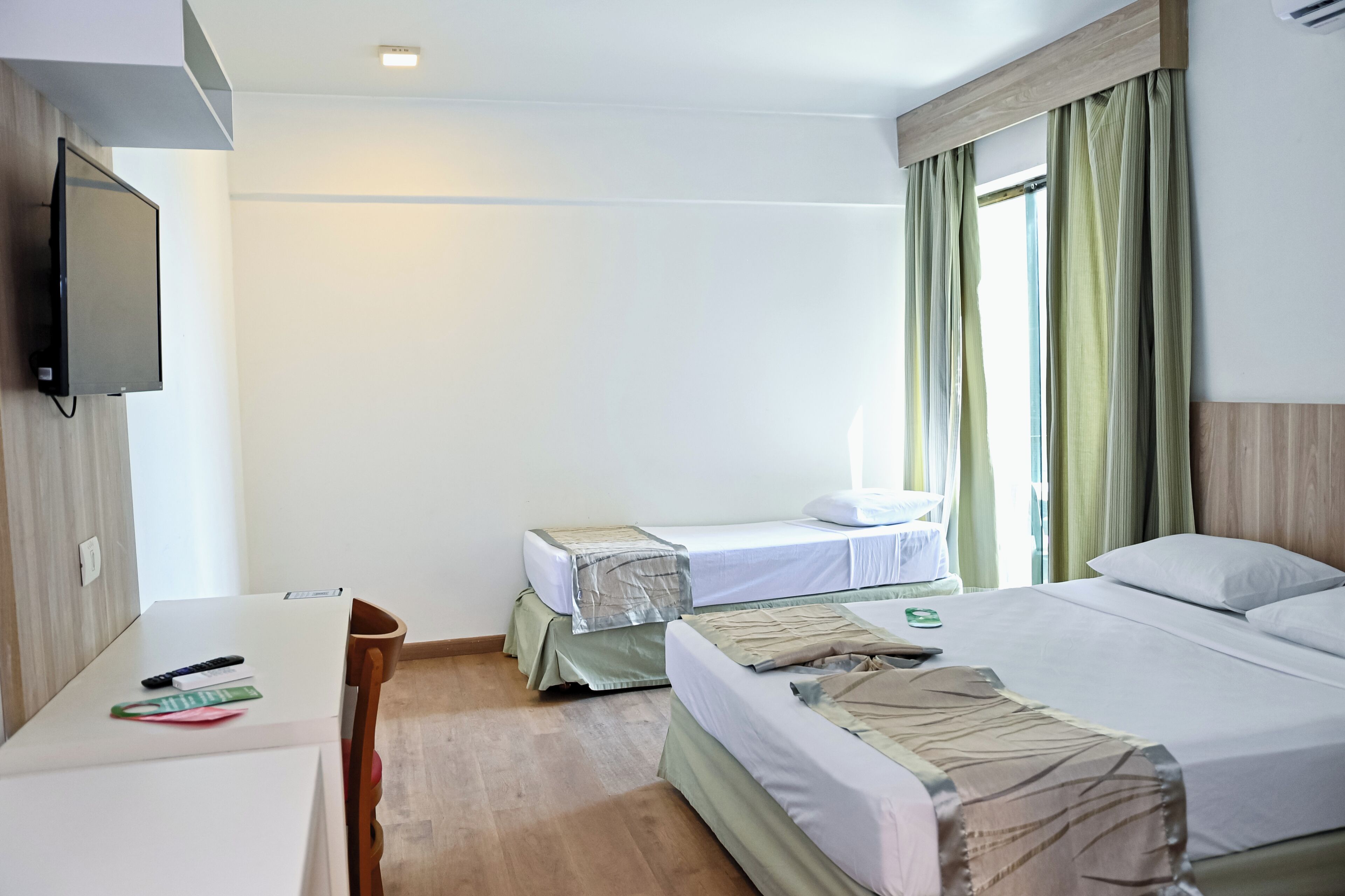 A hotel room with a bed, a desk, a chair, a television, and curtains.