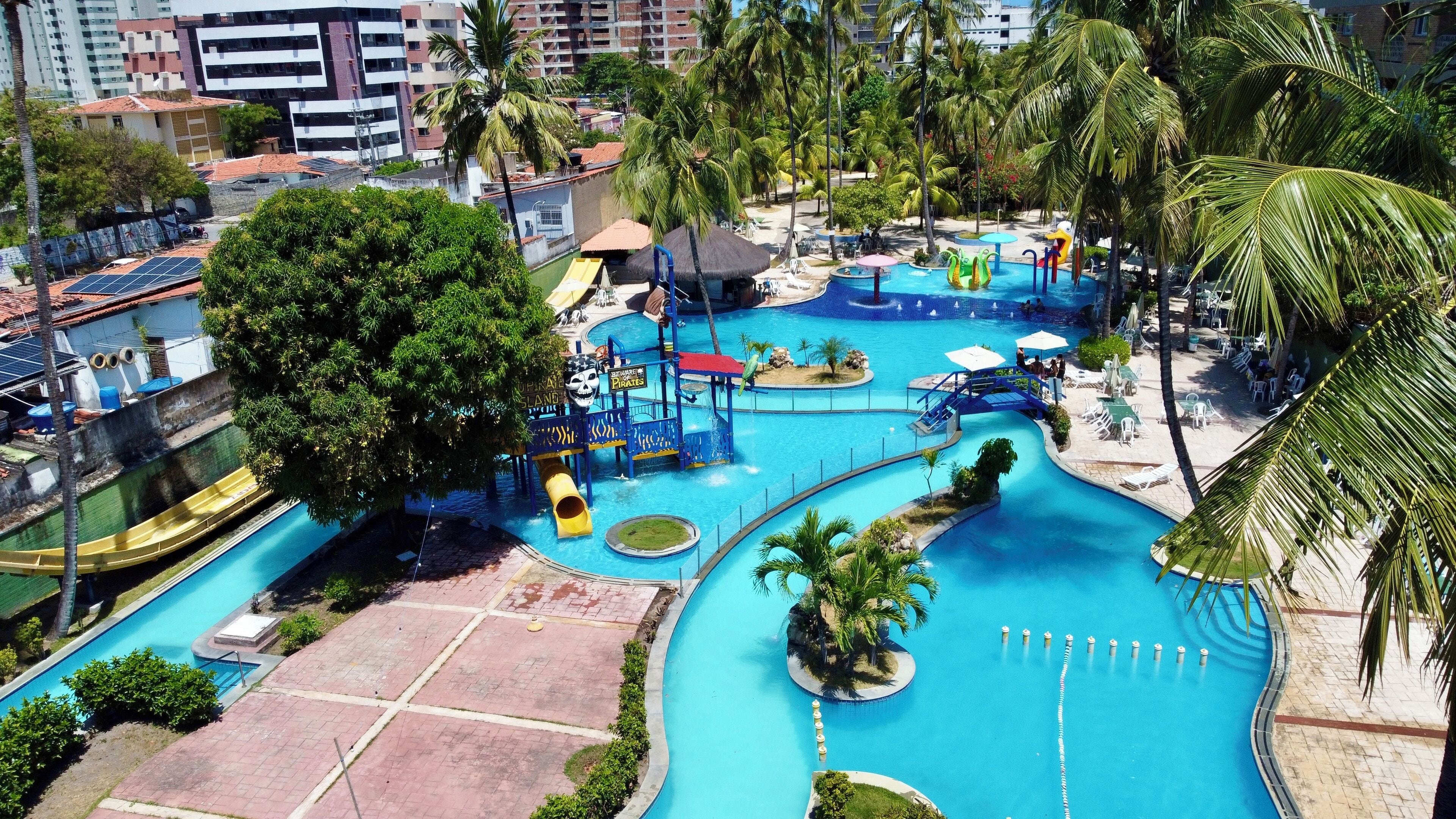 Una gran piscina exterior amb diverses tobogans aquàtics i una zona de jocs amb temàtica pirata.